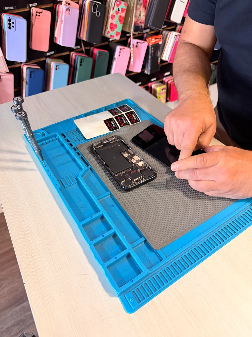 Técnico da SOS Mobile reparando um celular na bancada da loja